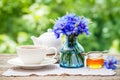 Tea cup, teapot, honey jar and summer bouquet of cornflower Royalty Free Stock Photo