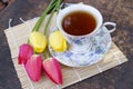 Tea cup, tulip flower, on wooden background