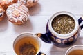 Tea cups, teapot and muffins on white wooden table, set teapot and brewed tea with cakes on table, green black herbal hot beverage