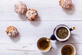 Tea cups, teapot and muffins on white wooden table, set teapot and brewed tea with dried leaves cakes on table, green black herbal Royalty Free Stock Photo