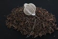 Tea filter on a chain with black tea on a pile of dry tea leaves. Tea filter - close-up of a kitchen accessory