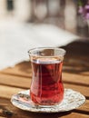 Tea in a glass of armudu on a saucer, located on a wooden table in the loggia. In the background are flowers . Bright sunny day. Royalty Free Stock Photo