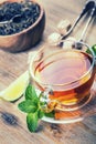 Tea in a glass cup, mint leaves, dried tea, sliced lime, cane sugar