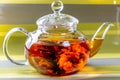 Tea in a glass teapot with a blooming large flower. Teapot with exotic green tea-balls blooms flower. Tea ceremony on green Royalty Free Stock Photo