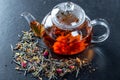 Tea in a glass teapot with a blooming large flower. Teapot with exotic green tea-balls blooms flower and dried tea and rose buds Royalty Free Stock Photo