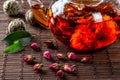 Tea in a glass teapot with a blooming large flower. Teapot with exotic green tea-balls blooms flower and dried rose buds with Royalty Free Stock Photo