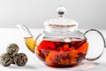 Tea in a glass teapot with a blooming large flower. Teapot with exotic green tea on a white background with dried balls-buds for Royalty Free Stock Photo