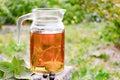 Tea in a glass teapot with green leaves of black currant on a wooden table against the background of green grass Royalty Free Stock Photo