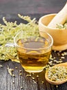 Tea of gray wormwood in glass cup with mortar on wooden board