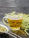 Tea of gray wormwood in glass cup with strainer on dark board
