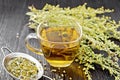 Tea of gray wormwood in glass cup with strainer on wooden board