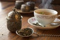 A tea infuser beside a cup of herbal tea Royalty Free Stock Photo