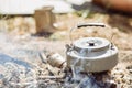 A tea kettle boiling over an open fire