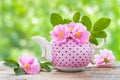 Tea kettle with bouquet of pink wild roses.