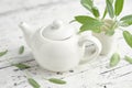 Tea kettle of healthy sage herbal tea, green leaves of salvia officinalis medicinal herb on white table Royalty Free Stock Photo