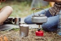 A tea kettle on a propane stove next to a metal cup Royalty Free Stock Photo