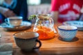 Tea in a large pot with a sprig. Tea with mango and orange on the table in a cafe