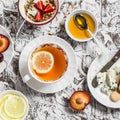 Tea with lemon, blue cheese, biscuits, honey, yogurt with granola and fruit on a light background. Royalty Free Stock Photo