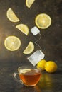 Tea with lemon in a glass cup on a dark background. The ingredients fall into the tea. The effect of levitation. Food on the move Royalty Free Stock Photo