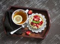 Tea with lemon tartlet with cream and strawberries in a vintage tray