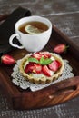 Tea with lemon tartlet with cream and strawberries in a vintage tray