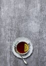 Tea with lemon in teacup with saucer and spoon at gray background