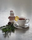 Tea with lemon in a white mug. The rustic table is decorated with spruce branches and a snowman figure Royalty Free Stock Photo