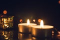 Tea Light Candles burning with bokeh lights on black background Royalty Free Stock Photo