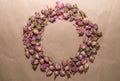 Tea made from dried buds and petals of a purple damask rose lies in the form of a wreath on a paper background in the center Royalty Free Stock Photo