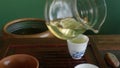 Tea master pouring fresh green tieguanyin brewing tea to bowl on wooden chaban.