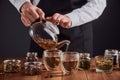 Tea master pouring spring tea with rose buds from a pot into glass cups