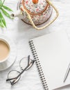 Tea with milk, teapot, notepad, glasses, pen, green flower leaf on white background, top view. Morning inspiration planning. Flat