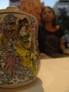 Tea mug with a lid, with beautiful asian painting on it and a finger handle, standing on white table