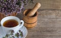 Tea with oregano on a wooden background and mortar with pestle for rubbing grass,with copy space Royalty Free Stock Photo