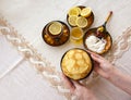 Tea in a painted Cup, on a saucer sliced lemon, pancakes, sour cream and a wooden spoon for overlaying. tea party in rustic style Royalty Free Stock Photo