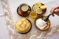 Tea in a painted Cup, on a saucer sliced lemon, pancakes, sour cream and a wooden spoon for overlaying. tea party in rustic style Royalty Free Stock Photo