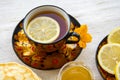 Tea in a painted Cup, on a saucer sliced lemon, pancakes, sour cream and a wooden spoon for overlaying. tea party in rustic style Royalty Free Stock Photo