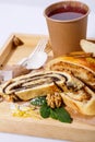 Tea in paper cup, disposable spoon and fork, poppy and apple strudel on a rustic wooden tray. Royalty Free Stock Photo