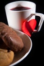 Tea cup of morning drink  waffles  biscuits and red heart on the black background. Romantic breakfast Royalty Free Stock Photo