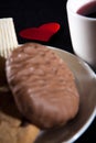 Tea cup of morning drink  waffles  biscuits and red heart on the black background. Romantic breakfast Royalty Free Stock Photo