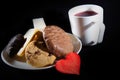 Tea cup of morning drink  waffles  biscuits and red heart on the black background. Romantic breakfast Royalty Free Stock Photo