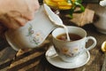 Tea party in rustic style. Pouring milk into tea cup. Royalty Free Stock Photo