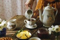 Tea party in rustic style. Pouring milk into tea cup. Royalty Free Stock Photo