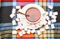 Tea party with sweets top, view. Mug filled with black brewed tea and spoon on colorful cozy plaid background. Mug with