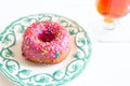 Tea and pink sugar donut on white wooden table Royalty Free Stock Photo