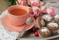 Tea in a porcelain pink cup, chocolate muffins, pink roses.