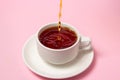 Tea is poured into a cup of tea on a pink background. Pour fresh tea. Royalty Free Stock Photo