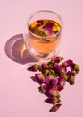 Tea with rose buds. Dry rose buds, a teacup on a pink background. dried rose buds on a pink surface.