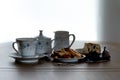 Tea Service & Fruit cake on a wooden table with the scene being backlit with natural light . The images a casual look with coins b Royalty Free Stock Photo