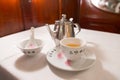 Tea service on a white table : Iron kettle, tea cup with hot tea, a soup bowl & special spoon